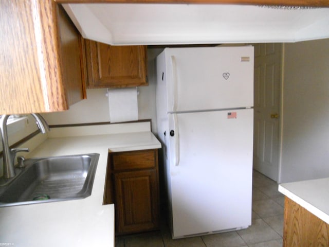 kitchen featuring a sink, light countertops, light tile patterned floors, and freestanding refrigerator