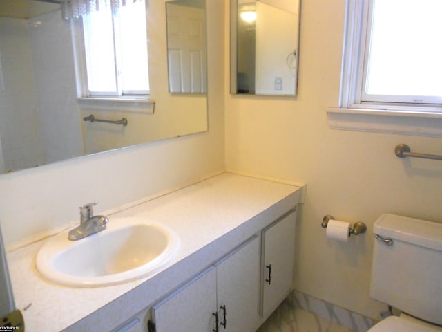 bathroom with a healthy amount of sunlight, vanity, and toilet