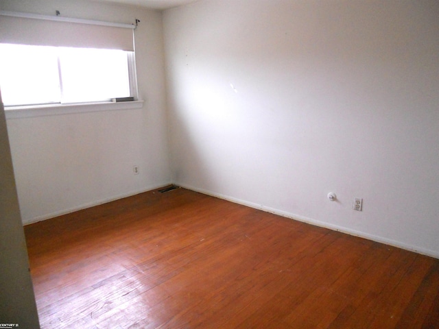 empty room featuring baseboards, wood finished floors, and visible vents