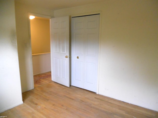 unfurnished bedroom with a closet, light wood finished floors, and baseboards