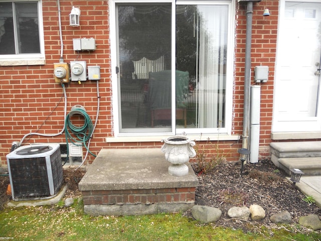 exterior details featuring brick siding, central AC unit, electric meter, and entry steps