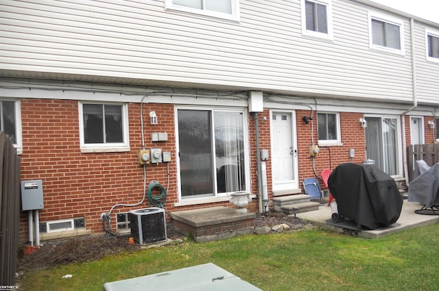 rear view of property featuring brick siding, cooling unit, a yard, and entry steps