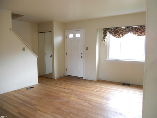 foyer with light wood-type flooring, a healthy amount of sunlight, stairway, and visible vents