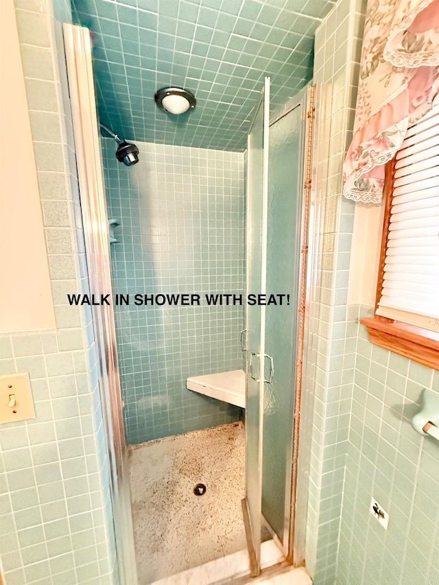 bathroom featuring tile walls and a shower stall