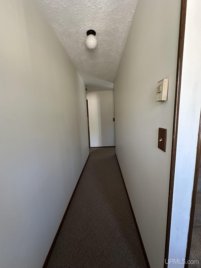 hall featuring carpet flooring and a textured ceiling