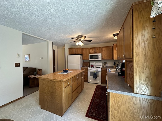kitchen featuring ceiling fan, white appliances, brown cabinetry, wooden counters, and a kitchen island