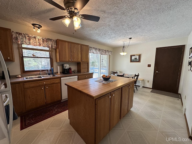 kitchen with brown cabinets, a sink, dishwasher, a textured ceiling, and butcher block countertops