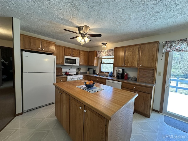 kitchen with ceiling fan, wooden counters, brown cabinets, light floors, and white appliances