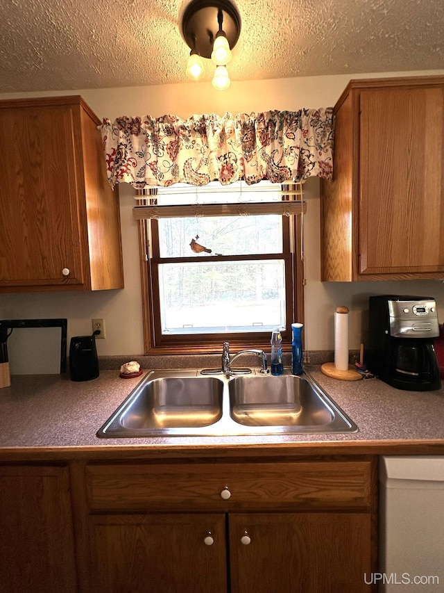 kitchen featuring a sink, a textured ceiling, dishwasher, and brown cabinets