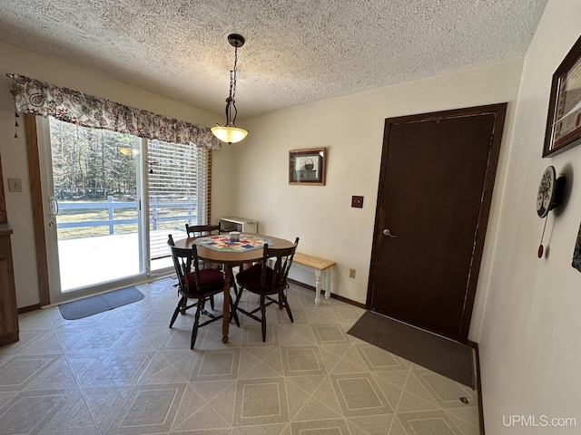 dining space with a textured ceiling, baseboards, and light floors