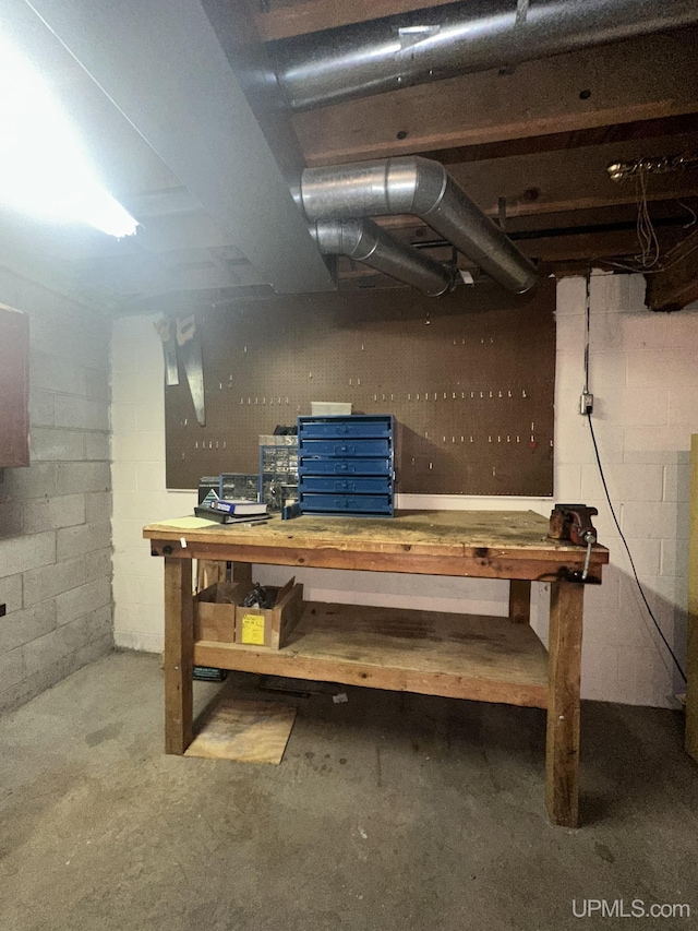 unfinished basement with concrete block wall and a workshop area