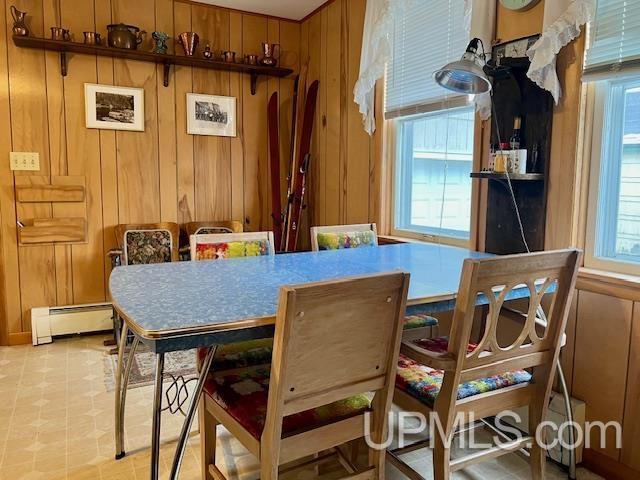 dining room with wooden walls and baseboard heating