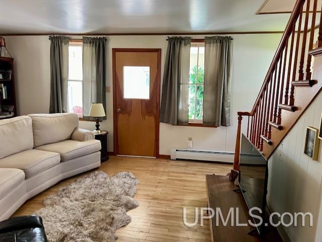 living area with ornamental molding, stairs, wood finished floors, and baseboard heating