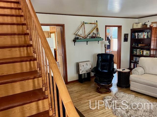 living area featuring stairs, baseboards, ornamental molding, and wood finished floors