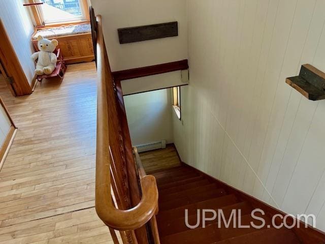 staircase with wood-type flooring and a baseboard heating unit