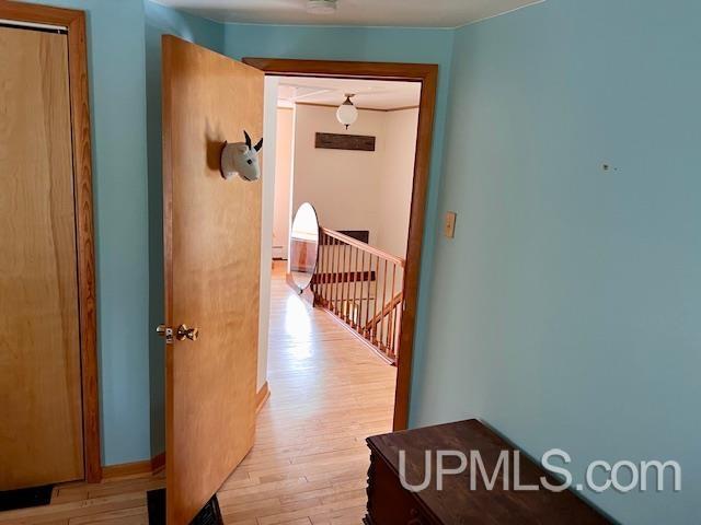 corridor with an upstairs landing and light wood finished floors