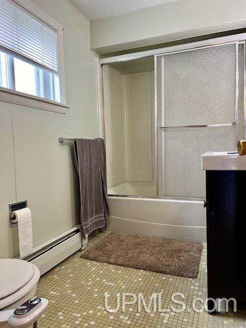 bathroom with baseboard heating, tile patterned floors, vanity, toilet, and enclosed tub / shower combo