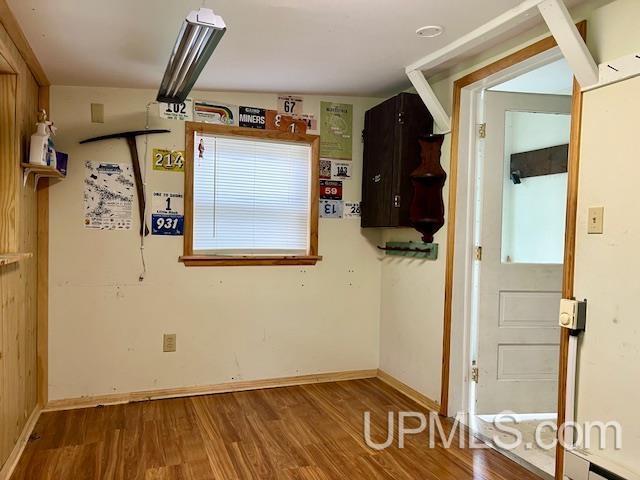 unfurnished room with baseboards and wood finished floors