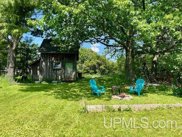 view of yard featuring an outdoor structure and an outdoor fire pit