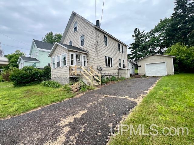 view of front of home with aphalt driveway, an outbuilding, a front yard, and a garage