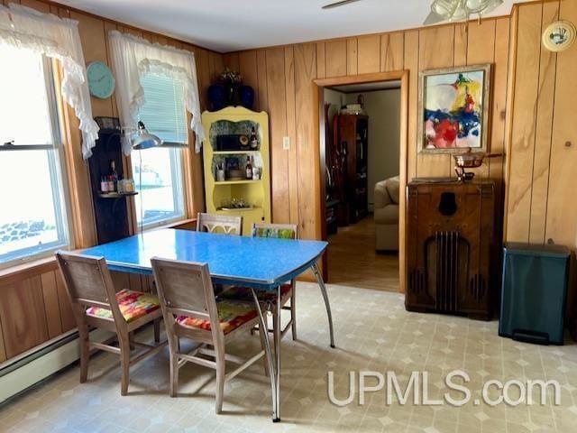dining area with wooden walls, light floors, and a baseboard radiator