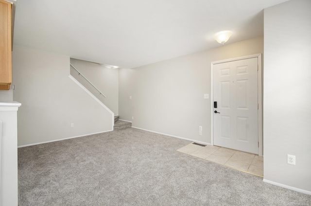 unfurnished living room with baseboards, light carpet, stairs, and visible vents