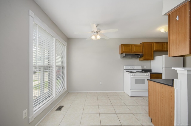 kitchen featuring ceiling fan, visible vents, brown cabinets, under cabinet range hood, and white appliances