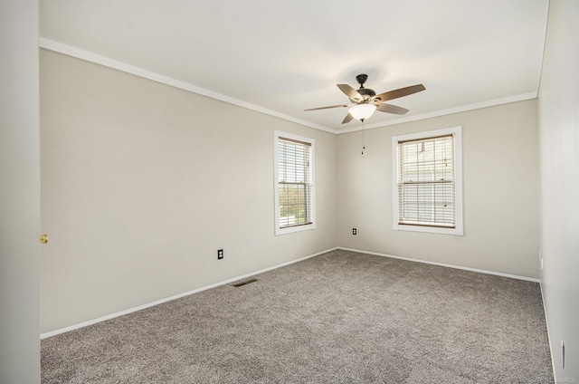 unfurnished room with carpet floors, a ceiling fan, baseboards, visible vents, and ornamental molding