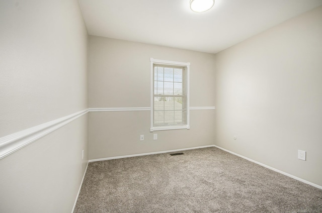 spare room with carpet floors, baseboards, and visible vents