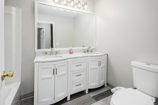bathroom featuring double vanity, a sink, a bathing tub, and toilet