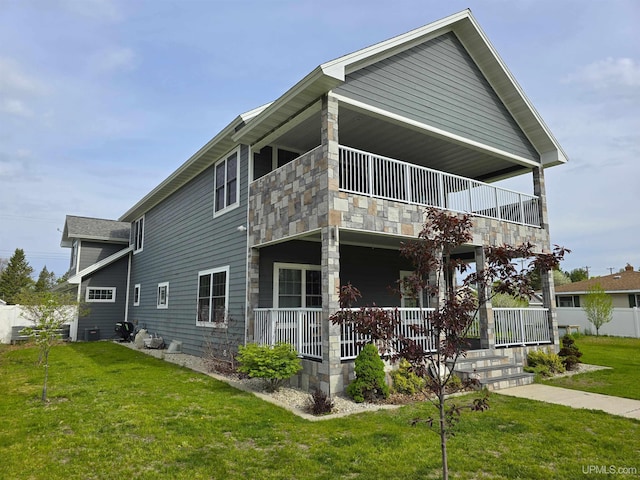 1812 Lake Shore Dr, Escanaba, MI 49829 - rear view of property with a balcony, covered porch, a yard, and stone siding