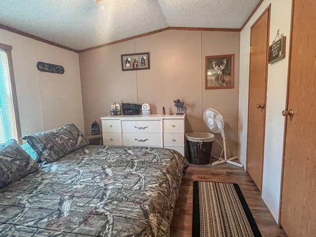 bedroom with vaulted ceiling, ornamental molding, a textured ceiling, and wood finished floors