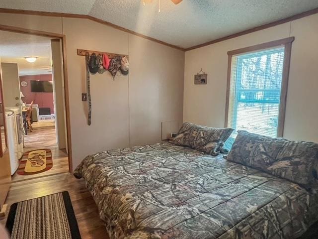 bedroom with lofted ceiling, wood finished floors, a textured ceiling, crown molding, and a ceiling fan