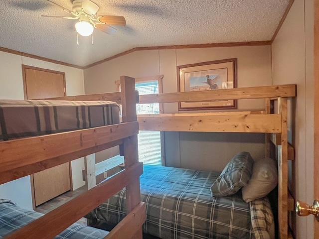bedroom with lofted ceiling, ornamental molding, and a textured ceiling