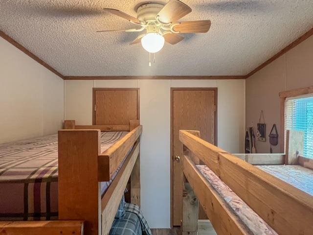 bedroom featuring vaulted ceiling, ornamental molding, a textured ceiling, and a ceiling fan