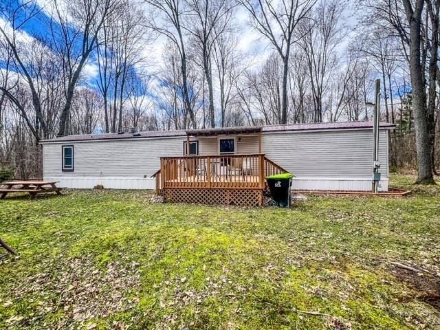 back of property with a deck and a lawn