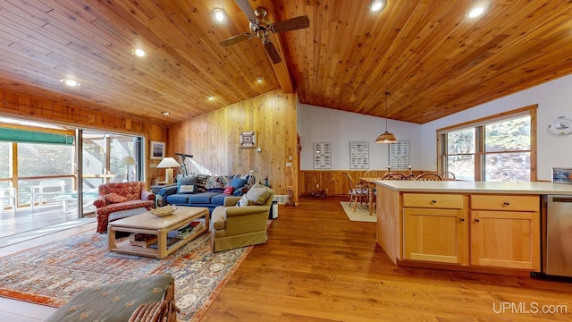 living room featuring wood walls, light wood-type flooring, vaulted ceiling with beams, and plenty of natural light