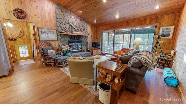 living room featuring a stone fireplace, wood walls, light wood-type flooring, and wooden ceiling