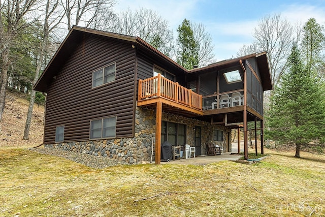 rear view of property featuring a yard, a patio, stone siding, and faux log siding