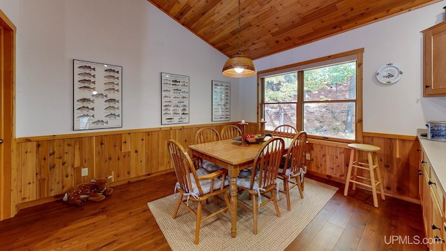dining area with vaulted ceiling, wooden ceiling, wooden walls, wood-type flooring, and wainscoting