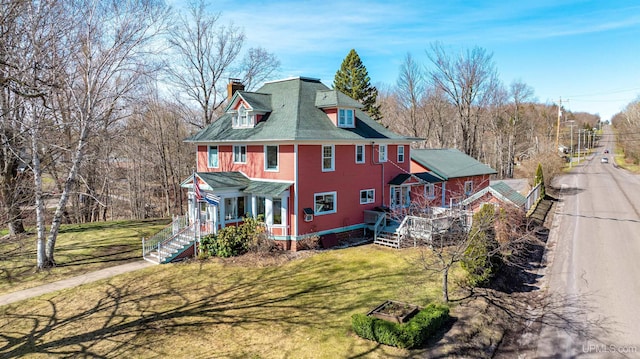 back of property featuring covered porch, a yard, a chimney, and stairs