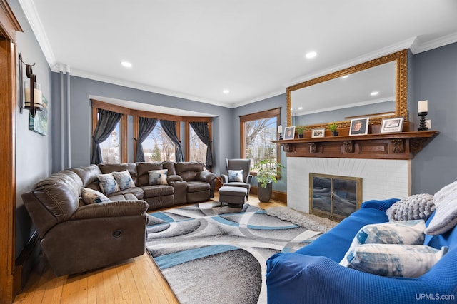 living room with ornamental molding, a brick fireplace, wood-type flooring, and recessed lighting