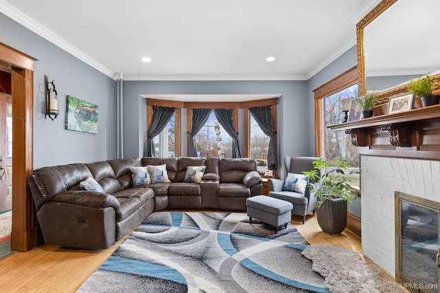 living room with crown molding, wood finished floors, a brick fireplace, and recessed lighting