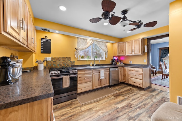 kitchen featuring ceiling fan, dark countertops, appliances with stainless steel finishes, and a sink