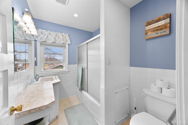 full bath featuring toilet, tile walls, wainscoting, and visible vents