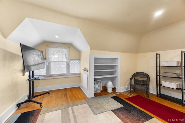 workout room with vaulted ceiling, baseboards, and wood finished floors