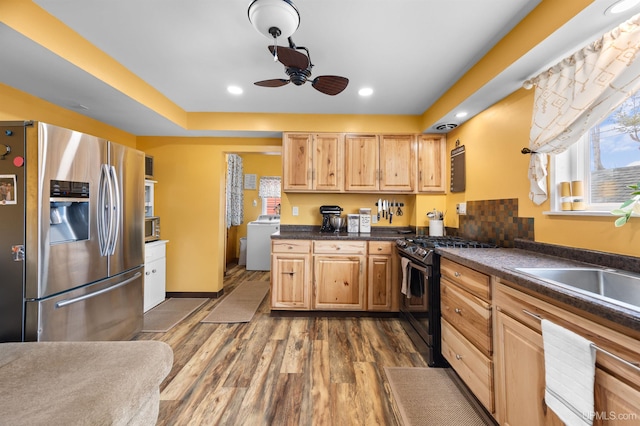 kitchen featuring washer / dryer, a ceiling fan, gas range oven, stainless steel fridge with ice dispenser, and dark countertops