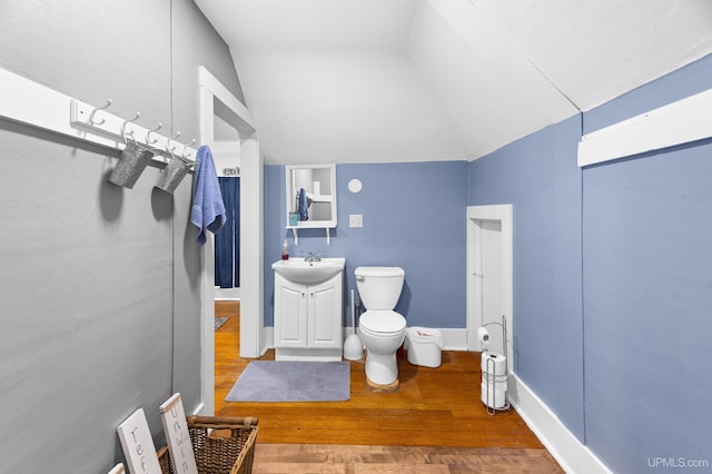 bathroom with vanity, toilet, wood finished floors, and lofted ceiling