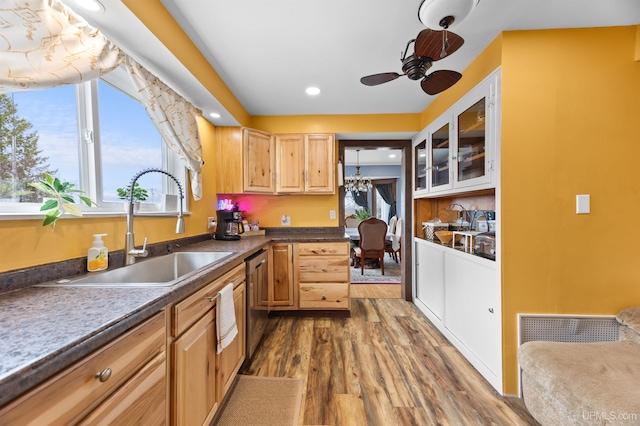 kitchen featuring glass insert cabinets, wood finished floors, a sink, ceiling fan, and dishwasher