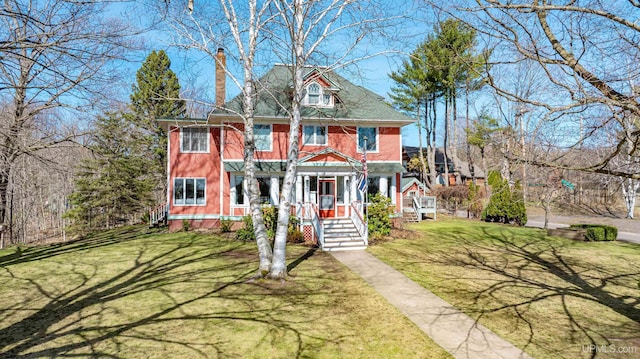 view of front of home featuring covered porch, a chimney, and a front yard